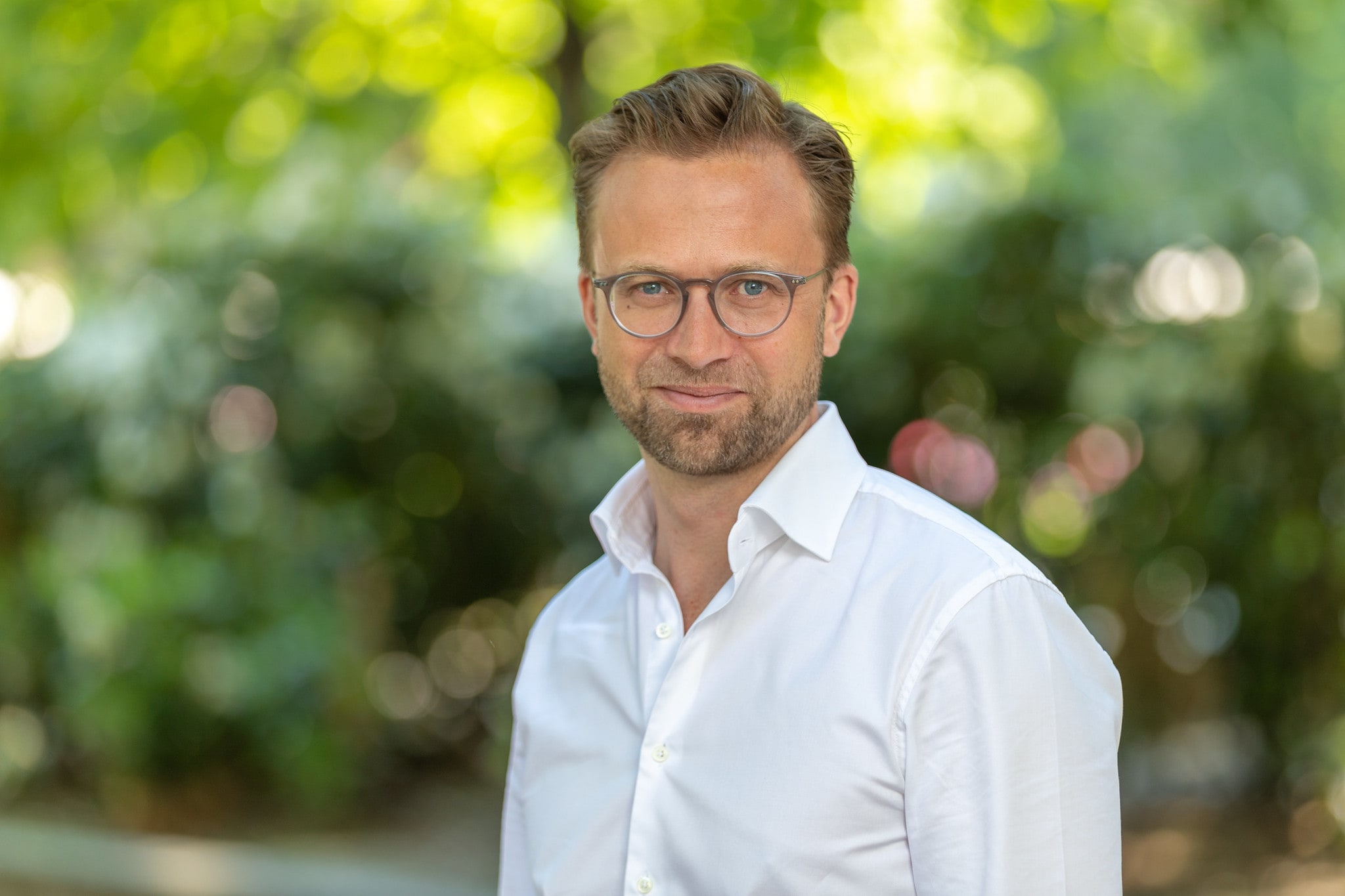 nikolai astrup med hvit skjort med grønn natur i bakgrunnen